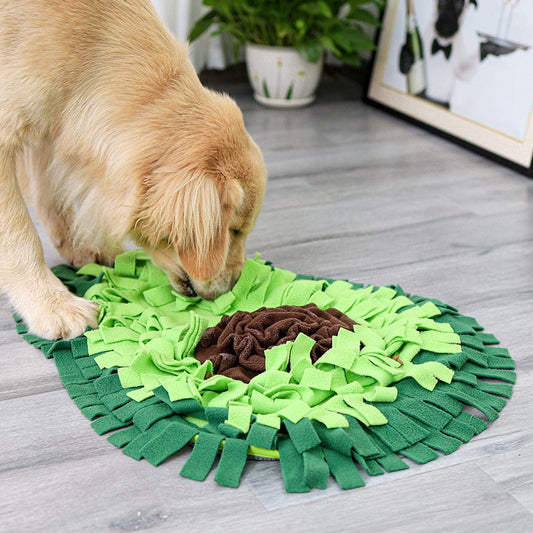 Dog playing with a green snuffle mat on a wooden floor.