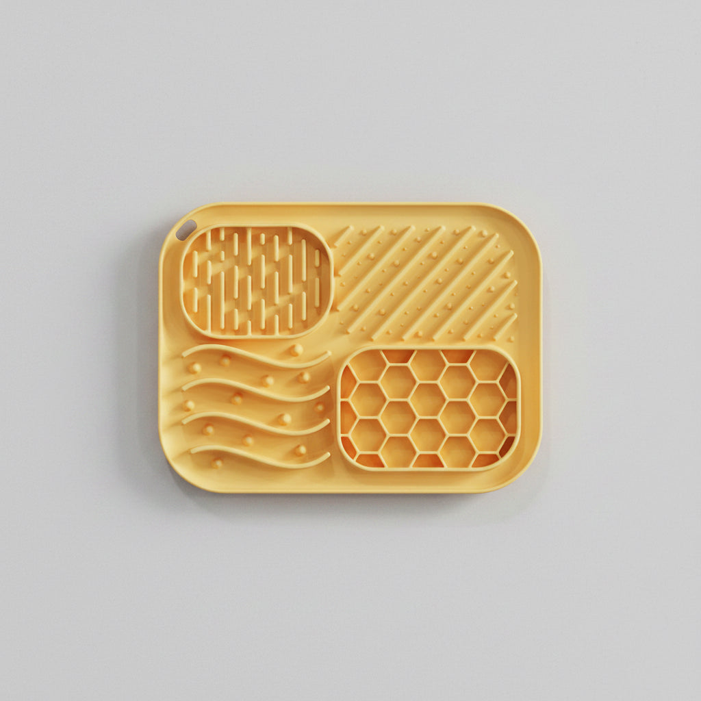 Yellow silicone baking tray with various textured sections on a white background