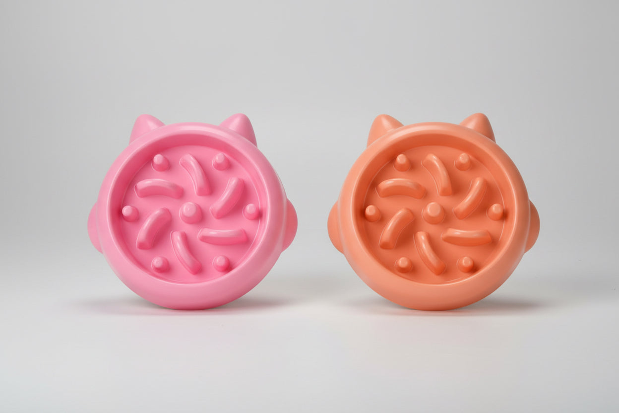 Two pink and peach-colored slow feeder bowl with cat ear designs on a white background.
