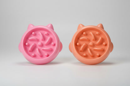 Two pink and peach-colored slow feeder bowl with cat ear designs on a white background.
